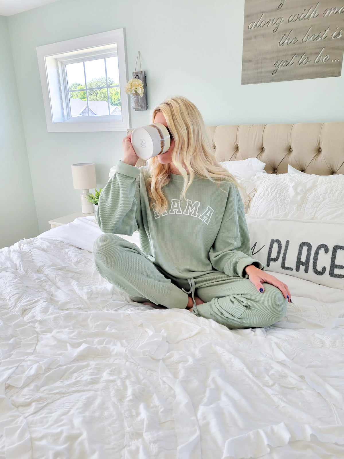 a mom drinking coffee on her bed, wearing a “Mama” sweatshirt