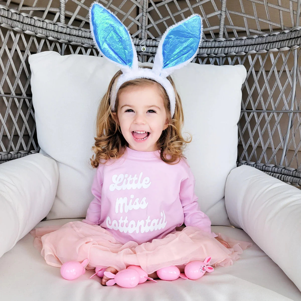 A kid wearing a pink graphic Easter tee and bunny headband