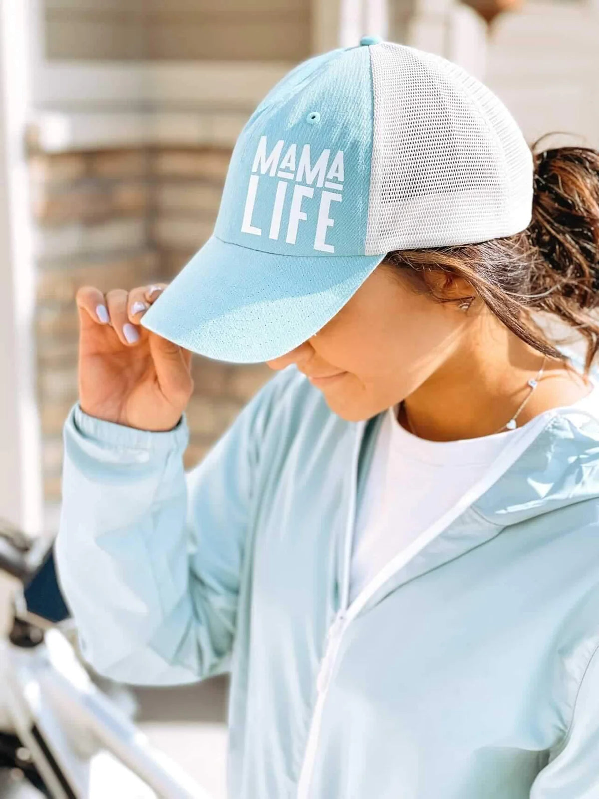 A mom wearing the Mama Life Aqua Trucker Hat
