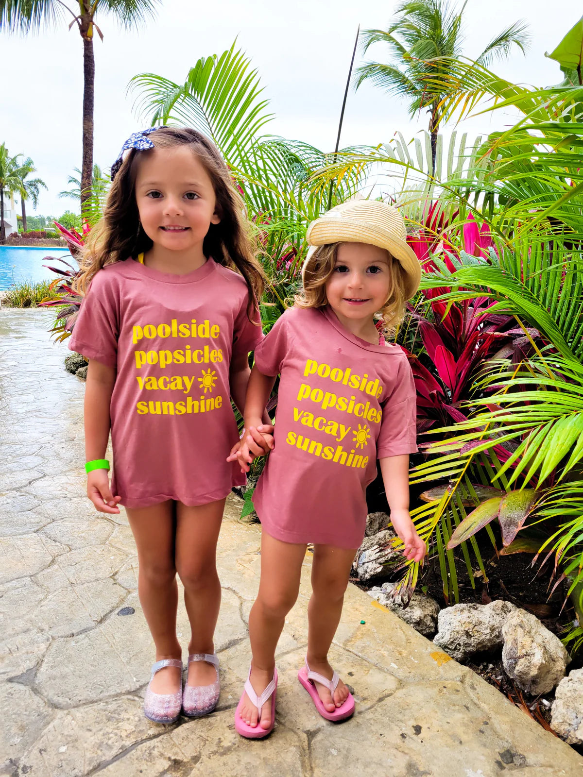 Two toddlers in pink spring graphic tees holding hands