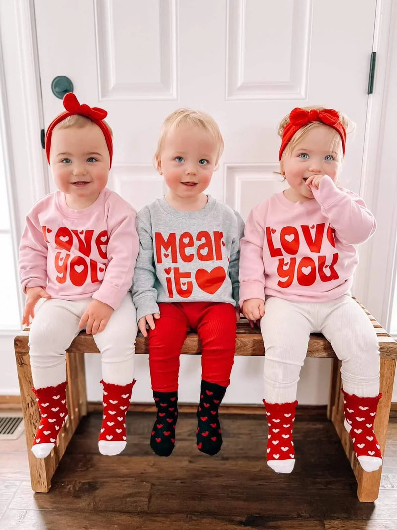 three toddlers wearing matching Valentine’s Day outfits