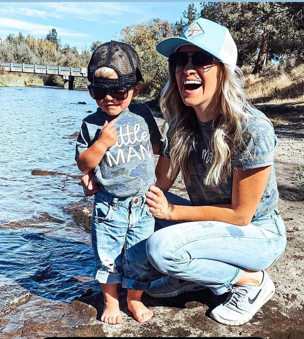 A child and mom at a river wearing matching camo outdoorsy shirts