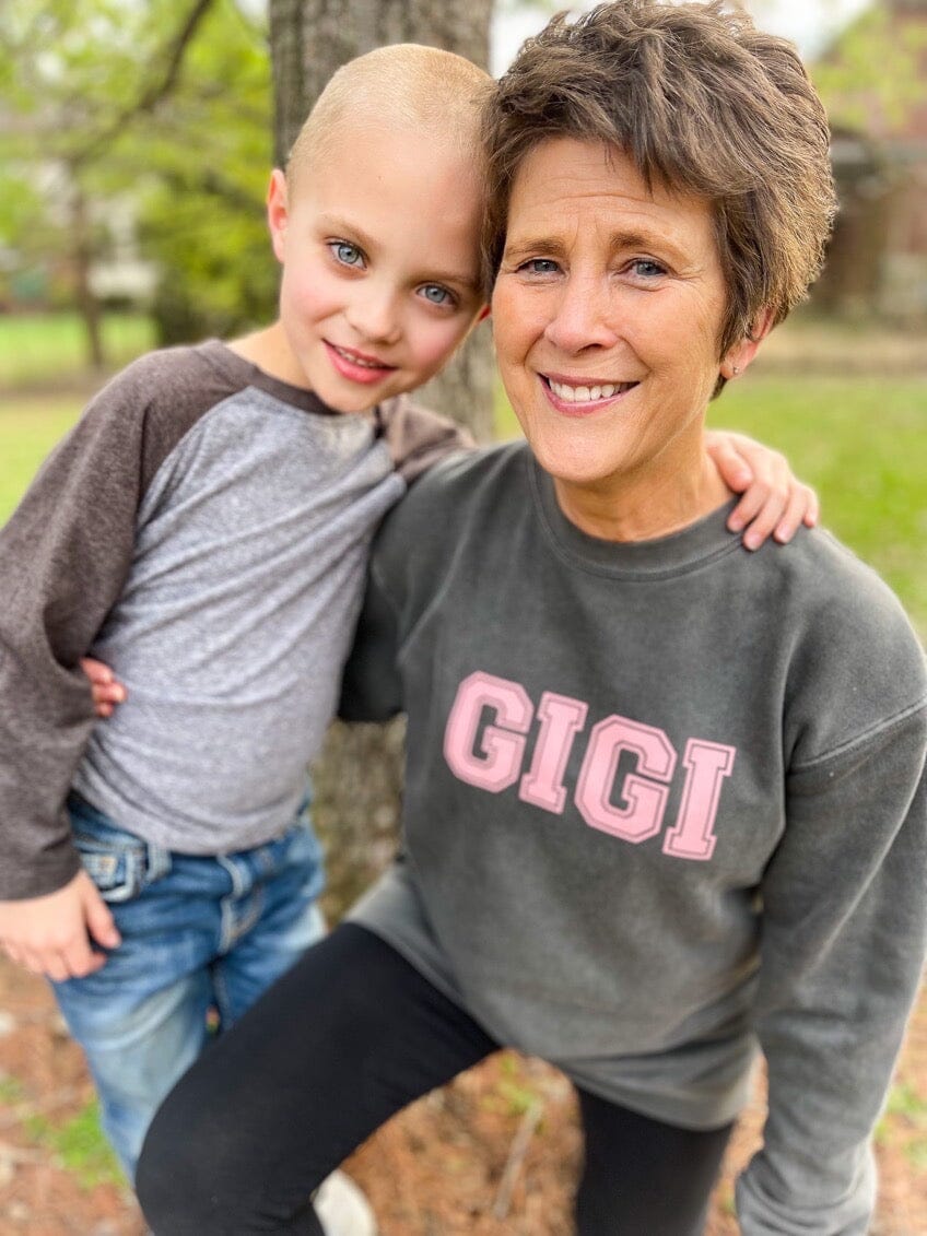 Grandma next to her grandkid wearing a sweatshirt that says “GiGi”