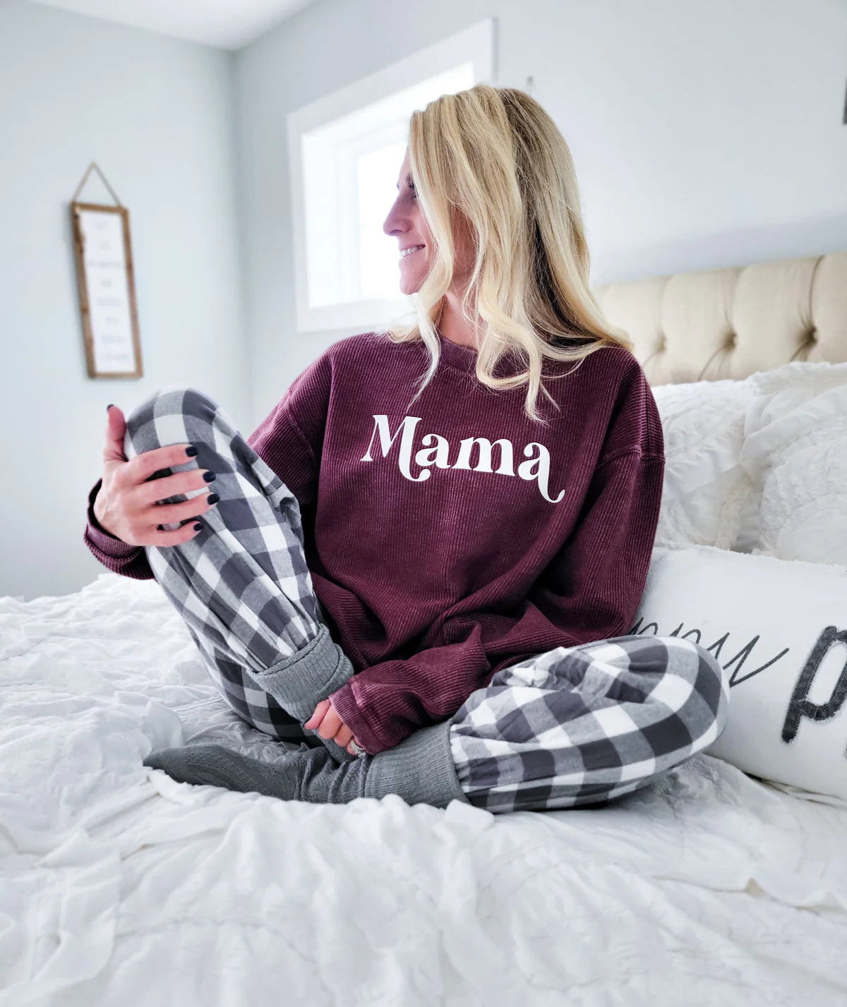 Woman wearing a “Mama” sweatshirt on bed