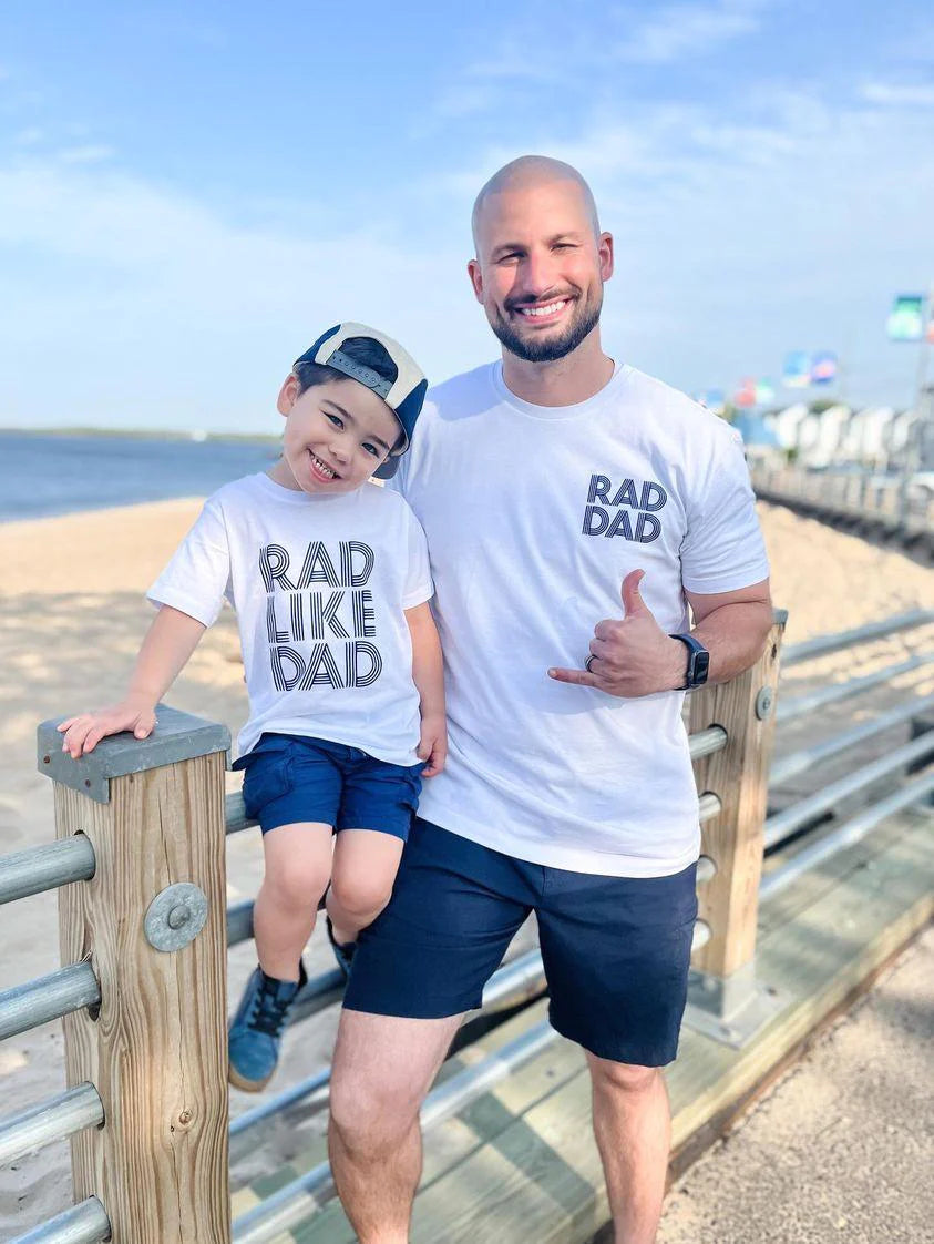 Dad and son wearing a set of white t-shirts that say “Rad Dad” and “Rad Like Dad”