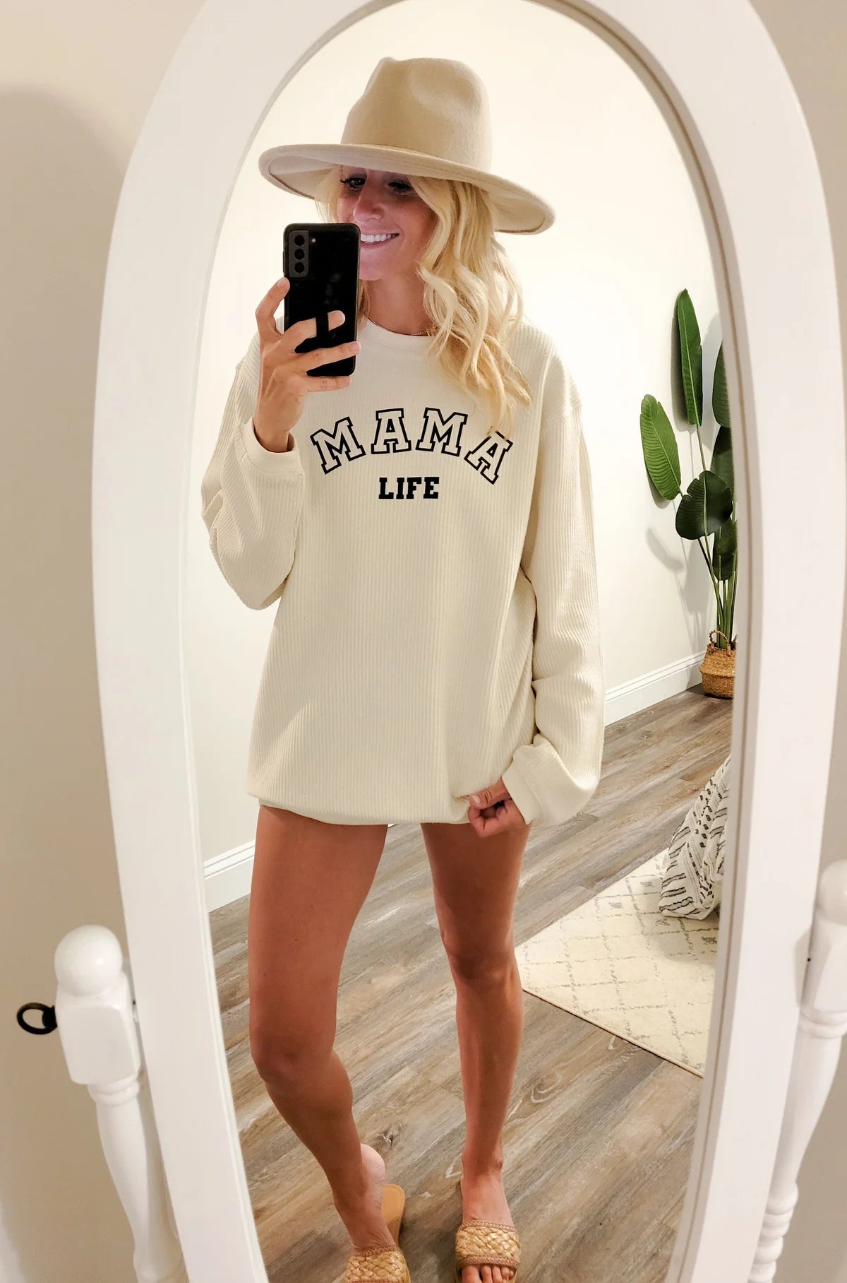 A woman wearing a white “Mama Life” sweatshirt in front of a mirror